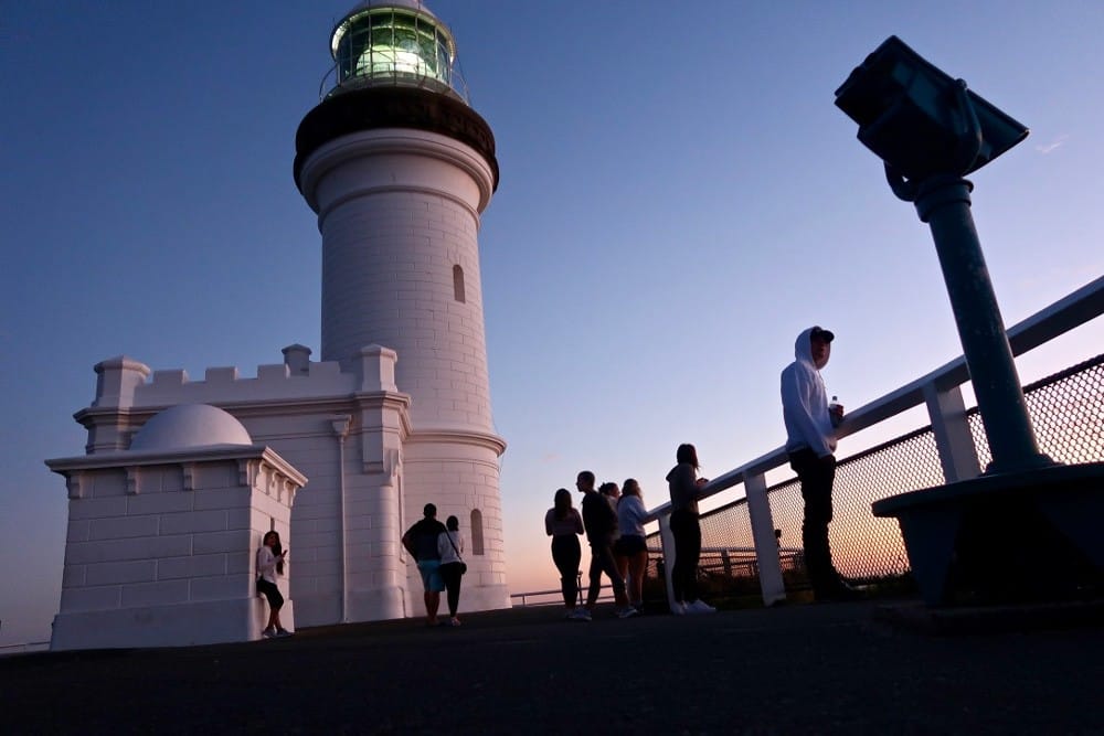 Vivir en Byron Bay Fotografía de la puesta del Sol en el faro de Byron Bay en Australia con gente
